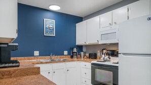 Une cuisine avec des meubles blancs, un four à micro-ondes, une cuisinière et une machine à café.