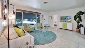 A modern living room with a sofa, armchairs, a coffee table, and a TV. - Tiki Lounge + Pool | 5 min to Beach & Las Olas (Fort Lauderdale)