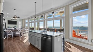 A spacious kitchen with a large island, a dining area, and a view of the ocean. - Hailo: Spacious 7-Bedroom Oceanfront Retreat in Oak Island, NC, perfect for up to 18 guests. (Oak Island)