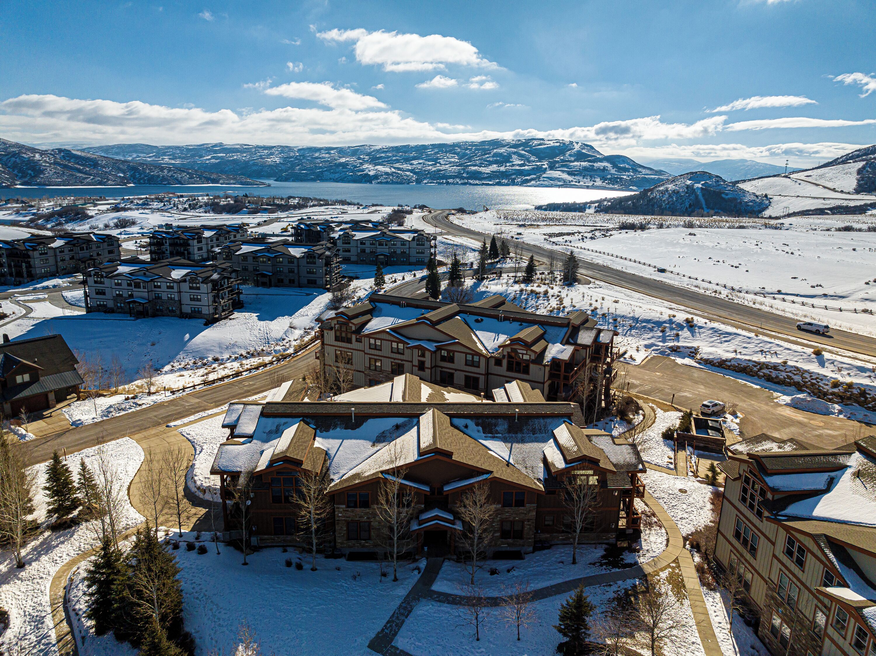 A large lodge with multiple buildings, a ski slope, and a lake in the background.