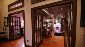 A spacious interior with wooden floors, a dining area with a table and chairs, and a kitchen in the background.