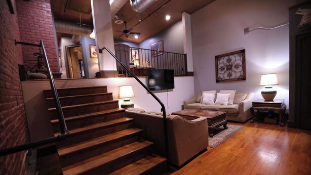 A staircase leading to a lofted area with a flat-screen TV mounted on the wall.