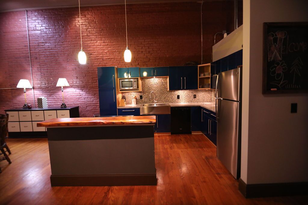 Una cocina moderna con una isla central, armarios de madera y pared de ladrillo.