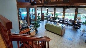 Un vestíbulo de hotel con una escalera, zona de estar y ventanas amplias.