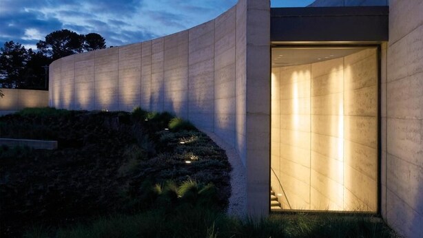 Un edificio moderno con fachada curva y una entrada bien iluminada.