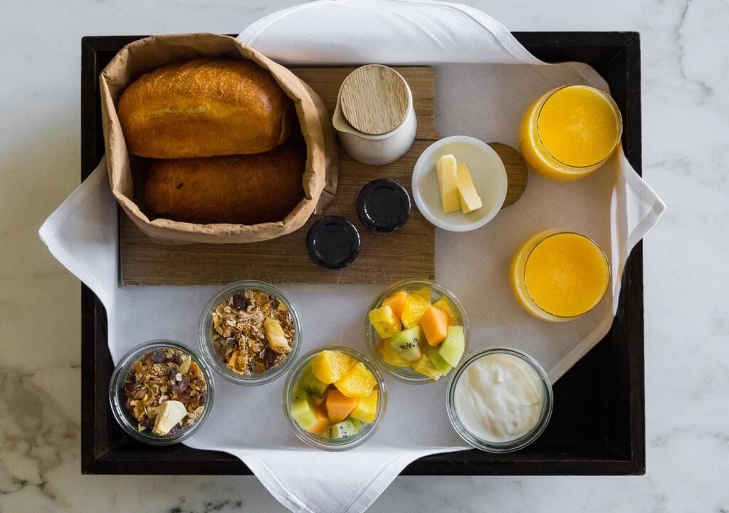 Ein Tablett mit Brot, Obst, Joghurt und Saft.