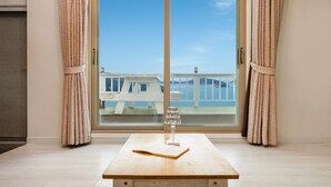 Une pièce dotée d’une grande porte-fenêtre coulissante donnant sur un balcon avec vue sur la mer.