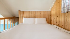 A bedroom with a wooden ceiling and a balcony railing. - Yeosu Grace Family Pension (Yeosu)