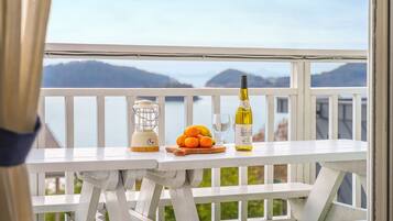 A balcony with a table set for a meal, a bottle of wine, and a lantern.