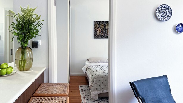 A modern, minimalist bedroom with a bed, bedside table, and a small bedside lamp. - Elegant Surry Hills Apartment: Steps to Cafes, City, & Sydney Icons (Darlinghurst)