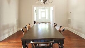 Ein Esszimmer mit einem langen Holztisch, sechs Stühlen und einer Kandelaber.
