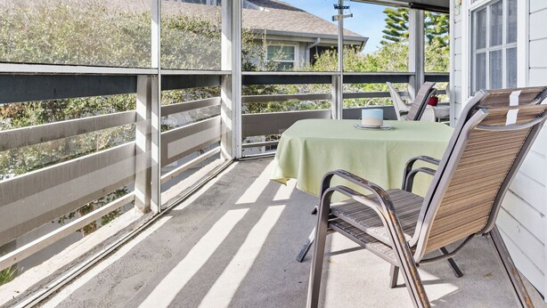 A covered patio with a table and chairs, a view of a house, and a 'Welcome' sign. - 273 Sea Woods Veranda 3BD - Keep Palm & Carry On (New Smyrna Beach)