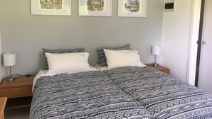 Makuuhuoneessa on kuviollinen päiväpeite, kaksi yöpöytää, joissa on lamput, ja seinällä on kolme kehystettyä kuvaa.