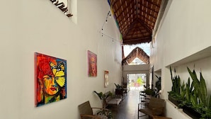 A corridor with wicker chairs, a wooden bench, and potted plants. - Coco Azul Hotel Boutique (Playa del Carmen)
