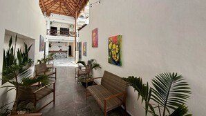 A spacious indoor area with a high ceiling, wicker furniture, and potted plants. - Coco Azul Hotel Boutique (Playa del Carmen)