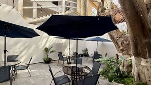 An outdoor patio area with round tables and chairs, surrounded by large umbrellas. - Coco Azul Hotel Boutique (Playa del Carmen)