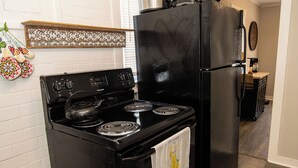 Een keuken met een zwart fornuis, een zwarte koelkast en een houten aanrecht.