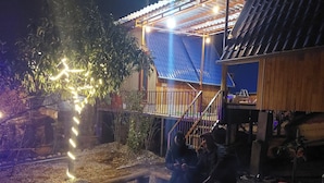 Un espace extérieur rustique, agrémenté d’une structure en bois, d’un foyer et d’un escalier menant à un deuxième niveau.