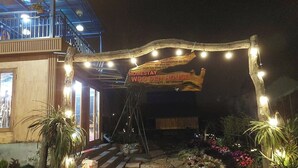 Une maison d’accueil avec une enseigne, un éclairage extérieur et des plantes en pot.