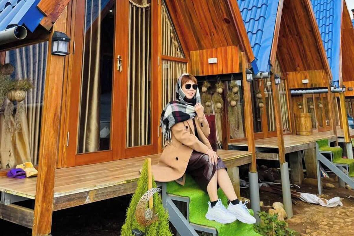 A wooden cabin with a sloped roof, a visible window, and a small outdoor seating area.