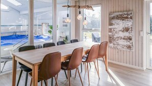 Een moderne eetruimte met een houten tafel en lederen stoelen, grote ramen en uitzicht op een zwembad.