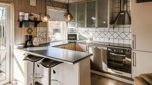Een moderne keuken met een centraal eiland, roestvrijstalen apparatuur en een raam met uitzicht op de omgeving.