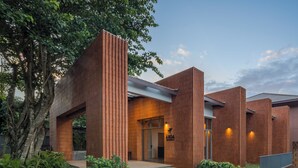 Un bâtiment moderne avec une façade en briques, une entrée en verre et un jardin bien entretenu.