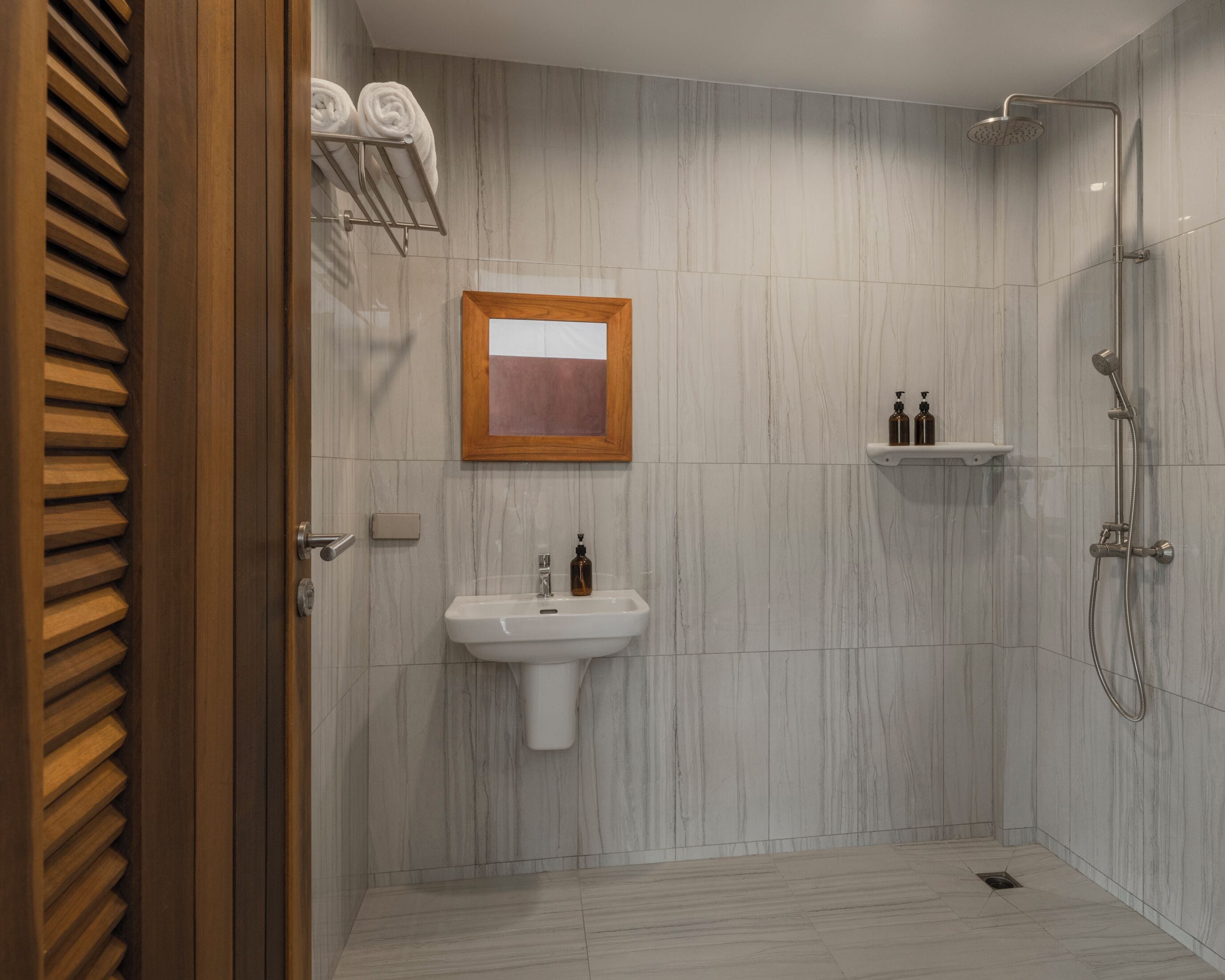 A modern bathroom with a marble floor, a sink, a shower, and a towel rack.
