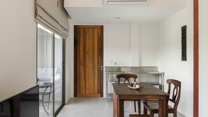 Une cuisine moderne avec une porte en bois, une table à manger avec des chaises et une cloison en verre.