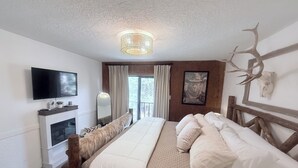 Une chambre dotée d’un grand lit, d’un téléviseur à écran plat, d’une cheminée et d’une décoration faite de bois de cerf.