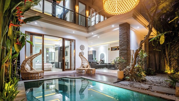 A modern indoor pool area with a glass pool, wicker furniture, and a staircase leading to an upper level. - Villa Liamax (By JB Villas) (Bali)