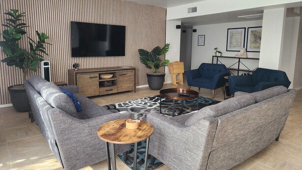 Una sala de estar moderna con un sofá gris, una mesa de centro, un televisor y un aparador de madera.