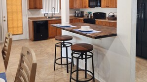 Una cocina moderna con armarios de madera, una isla central con taburetes y un comedor con mesa y sillas.