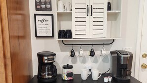 Un espacio tipo cocina con rincón para café, que incluye cafetera, tazas y la carta de café.