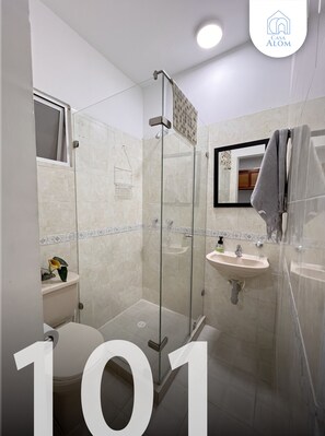 Ein modernes Badezimmer mit einer Duschkabine, einer Toilette und einem Waschbecken mit Spiegel.