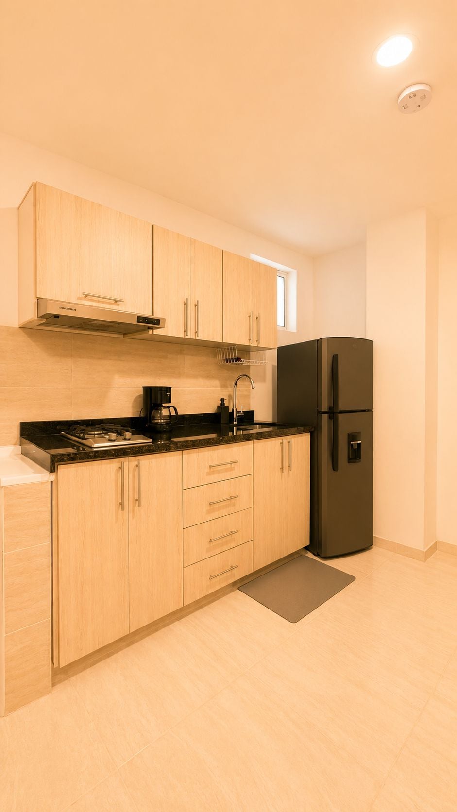 Una cocina moderna con armarios de madera, un refrigerador negro y una estufa a gas.