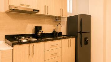 Una cocina moderna con armarios de madera, un refrigerador negro y una estufa a gas.