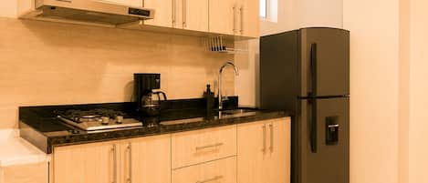 Una cocina moderna con armarios de madera, un refrigerador negro y una estufa a gas.