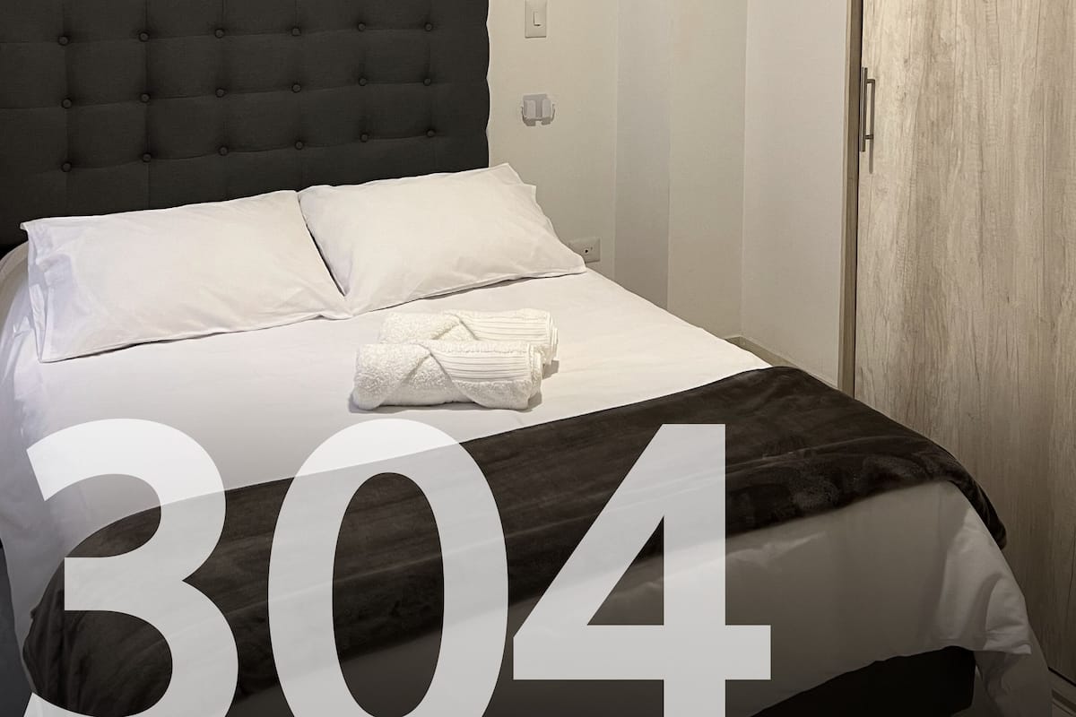 A hotel room with a large bed, a dark headboard, and three paintings of yellow flowers on the wall.