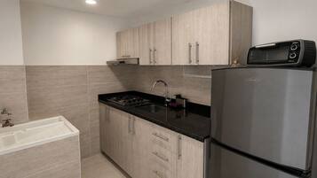 Una cocina moderna con un refrigerador de acero inoxidable, un microondas y una estufa a gas.