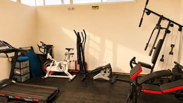 Un gimnasio con equipo de ejercicio, incluyendo cinta de correr, bicicleta estática, elíptica y máquinas de pesas.