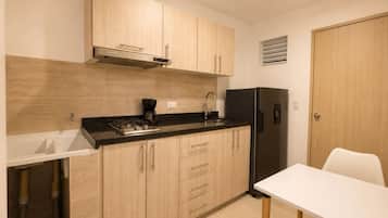 A compact kitchen with a gas stove, a coffee maker, a sink, and a refrigerator.