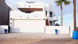 A modern building with a white facade, a garage door, and two blue planters.