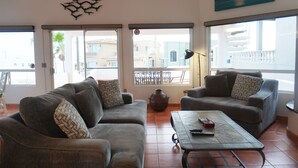 A living room with two grey sofas, patterned cushions, a large vase, and a coffee table with remotes.
