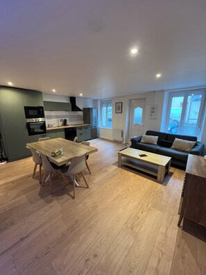 Enjoy a spacious living area with a dining table and comfortable seating, a well-equipped kitchen with microwave, oven, and dishwasher, and a cozy seating area with a sofa and coffee table.