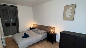 Une chambre à coucher comprenant un lit, des tables de chevet, un radiateur, une armoire et une œuvre d’art accrochée au mur.