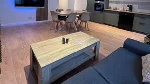 Un salon moderne avec un téléviseur à écran plat, une table basse en bois et un canapé bleu.