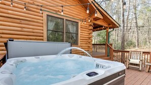 Un bain à remous sur une terrasse en bois, avec un chalet en bois en arrière-plan.