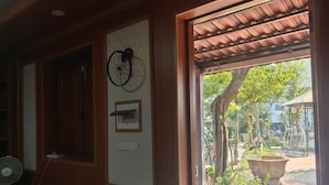 A room with a wooden door, a wall clock, and a fan. - Homestay nha go Lan Anh (Tu Vu)