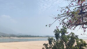 A beach with a clear view of the water and distant hills. - Homestay nha go Lan Anh (Tu Vu)